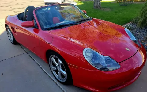 Roter Porsche Boxster Cabriolet. Die glänzende Karosserie spiegelt den Himmel wider. Ein Blick auf die potenziellen Porsche Service Kosten.