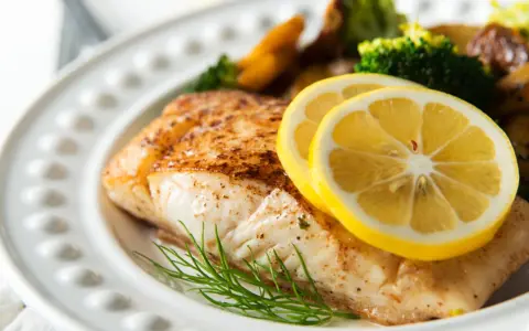 Pieczony halibut z cytryną i koperkiem, podany z pieczonymi ziemniakami i brokułami. Zdrowe danie, które nie musi mieć wielu halibut kcal.