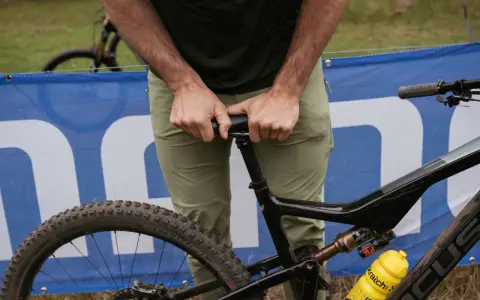 A rider adjusts their seat on a full-suspension bike, ready for an enduro mountain biking adventure.