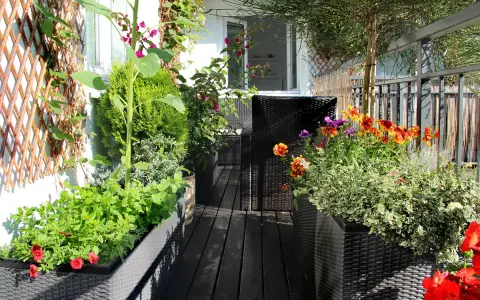 Un vibrante huerto urbano en un balcón, con girasoles, flores coloridas y plantas verdes en macetas.