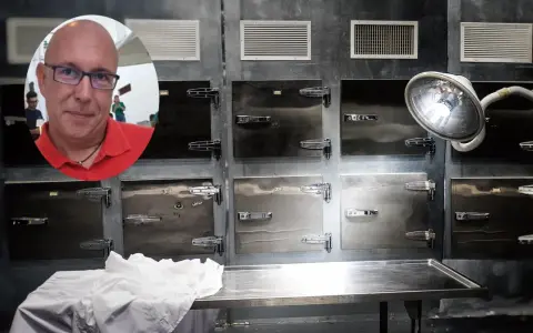 Mężczyzna w okularach i czerwonej koszulce na tle chłodni, gdzie odbywa się balsamacja.