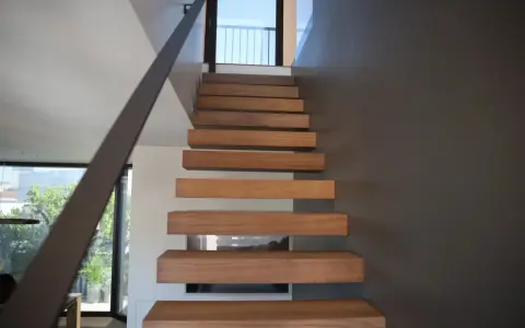 Moderna scala interna con gradini in legno sospesi, un'idea di design minimalista e funzionale.
