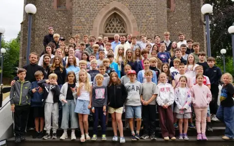 Große Gruppe von Kindern und Jugendlichen vor einer Kirche, die an einem christlichen Ferienlager teilnehmen.