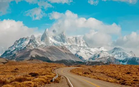 Droga wije się przez trawiastą równinę w kierunku majestatycznych, ośnieżonych szczytów Patagonii. Idealne miejsce dla marki Patagonia.