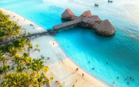 Rajska plaża na Zanzibarze z palmami i restauracją na wodzie. Sprawdź aktualne zanzibar ceny, by zaplanować wymarzone wakacje.