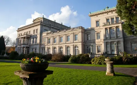 Prachtvolle Krupp Villa mit gepflegtem Garten und Blumenkübeln im Sonnenschein.