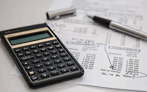 Calculadora y bolígrafo sobre un balance de situación. El balance de situación muestra cifras de inversión y valor al cierre del año.