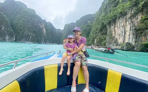 Mom and daughter in Thailand con bambini, navigano su un motoscafo tra scogliere verdi e acque turchesi.