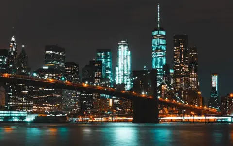 Il Ponte di Brooklyn illumina la **new york city vita notturna**, con grattacieli scintillanti che si riflettono sull'acqua scura.