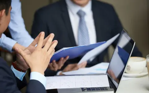 Personas discuten documentos y gráficos, quizás sobre la demora de calificación de incapacidad permanente.