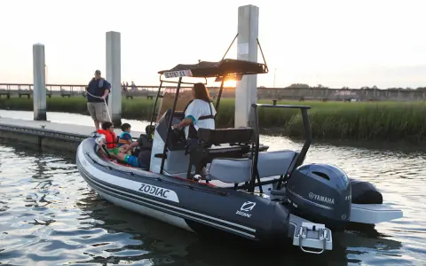 Bateau Zodiac prêt pour l'aventure, son hypalon garantissant une longue durée de vie. Famille à bord, profitant du coucher de soleil.
