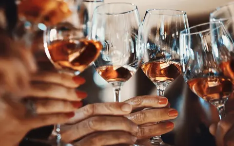 Hände halten Gläser mit Roséwein. Ein Genuss ohne Sulfite, vegan und köstlich.
