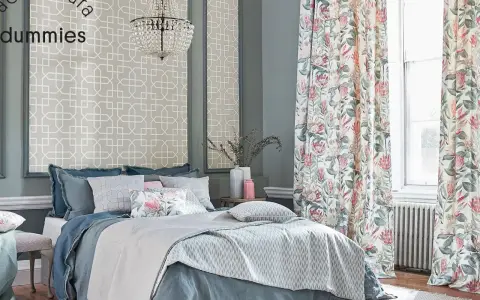 Cama elegante con ropa de cama azul y cojines florales, cortinas de proteas y papel tapiz geométrico. Un kilim Maimana aportaría calidez a este espacio.