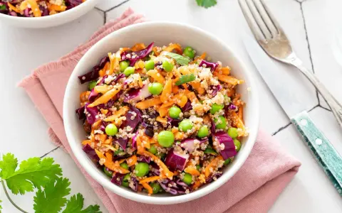 Salade quinoa colorée avec carottes râpées, chou rouge, petits pois et edamame. Un plat sain et savoureux.