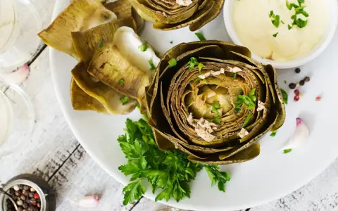 Deliciosas alcachofas al horno, tiernas y doradas, servidas con una cremosa salsa y perejil fresco. Un plato perfecto para disfrutar.
