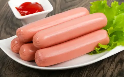 Kilka parówek na talerzu z sałatą i ketchupem. Idealne do szybkiego obiadu, dowiedz się, jak ugotować parówki.