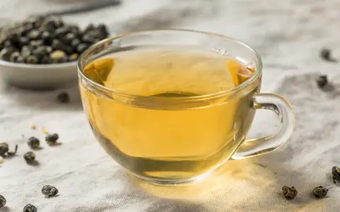 Zaparzona herbata oolong w szklance, obok miseczka z suszonymi liśćmi. Odkryj niezwykłe herbata oolong właściwości.