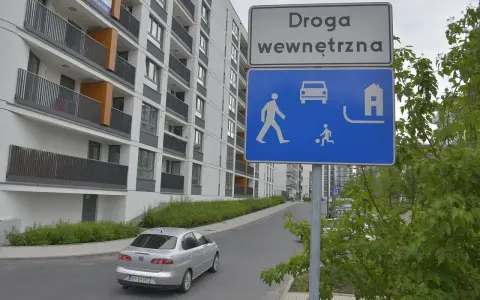 Droga wewnętrzna w terenie zabudowanym. Znak informuje o ruchu pieszych, samochodów i domów.
