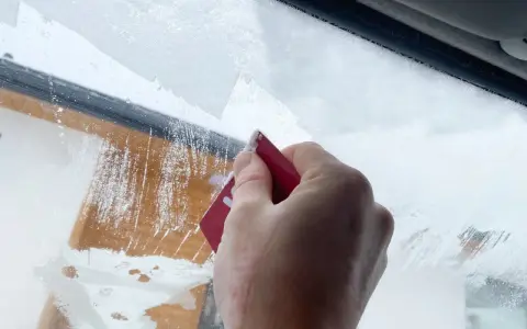 Dłoń zeskrobuje szron na szybie, odsłaniając fragmenty drewnianej elewacji. Zima daje się we znaki.
