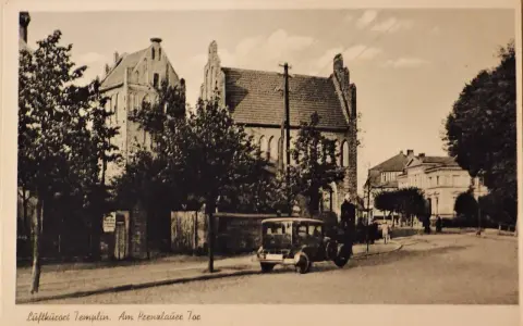 Alte Ansicht der Templiner Altstadt mit einem historischen Auto auf der Straße und markanten Gebäuden im Hintergrund.