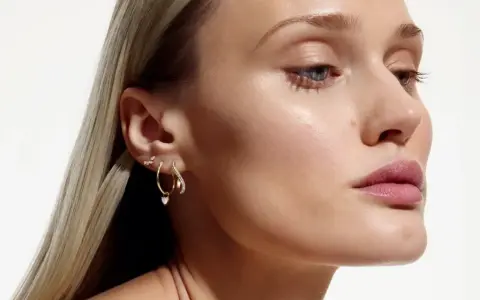 Delikatne kolczyki z kwiatami i serduszkiem, zdobiące ucho modelki, dodają subtelnego blasku.