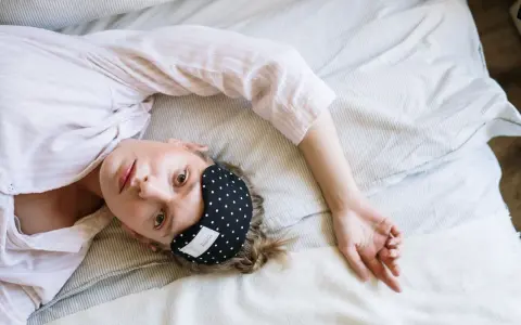 Donna con mascherina per dormire, cerca rimedi per l'insonnia da stress.