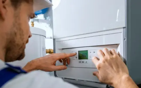 Técnico ajustando la temperatura en un calentador de gas butano. La pantalla digital muestra 30.0 grados.