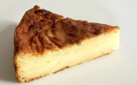 Una fetta di torta di mele fondente, con strati dorati e un ripieno cremoso.