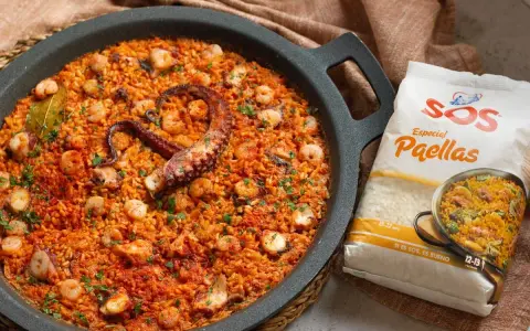 Paella de marisco con un tentáculo de pulpo visible, gambas y trozos de calamar. Al lado, un paquete de arroz SOS Especial Paellas.