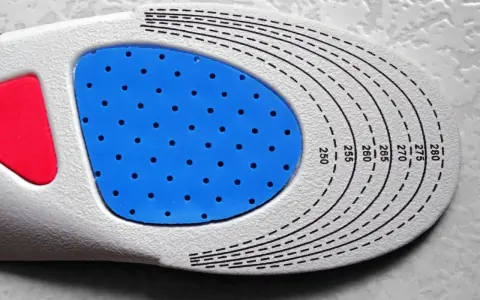 Semelle orthopédique personnalisée, une ordonnance podologue pour un confort optimal. La semelle présente une zone bleue perforée et des repères de taille.