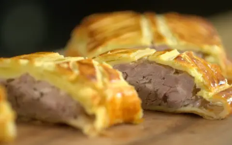 Tranche d'un plat lorrain, une viande savoureuse enveloppée dans une pâte feuilletée dorée.