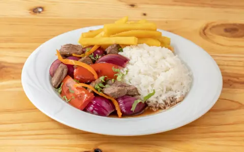 Lomo saltado con arroz blanco, papas fritas, carne, cebolla roja y tomate. Un plato peruano delicioso.