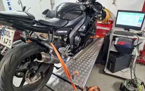 Czarny motocykl na hamowni, przygotowany do **blokowania motocykla na A2**. Pomiar mocy i momentu obrotowego.