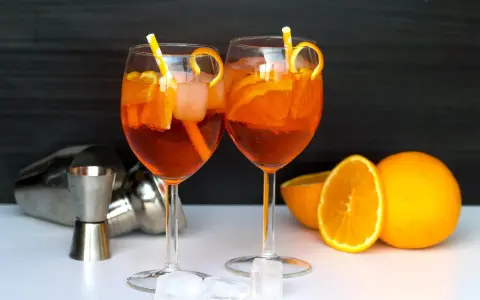 Deux Aperol Spritz prêts à déguster, avec des oranges fraîches et des glaçons. La recette parfaite pour un apéritif ensoleillé.