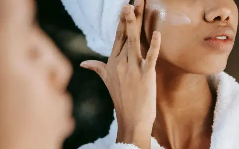 Donna applica crema viso con hydroxypinacolone retinoate, per una pelle luminosa e giovane.