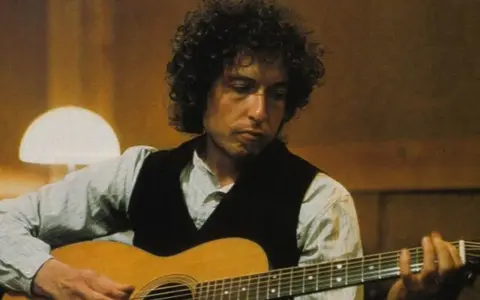 Bob Dylan gra na gitarze, tworząc swoje legendarne utwory.