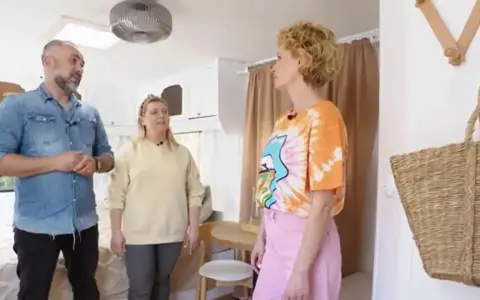 Trzy osoby omawiają remont przyczepy kempingowej. Wnętrze jest jasne, z widocznym łóżkiem i meblami.