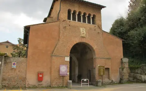 The imposing facade of Tre Fontane Abbey, with its arched entrance and upper loggia, stands against a cloudy sky.