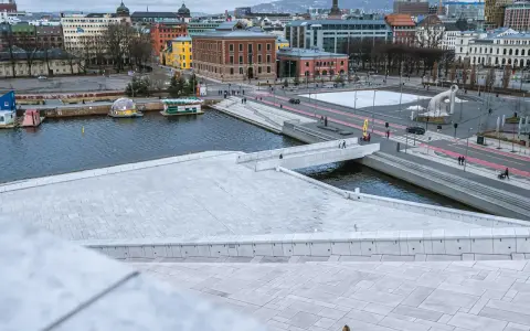 Widok z punktu widokowego Oslo na nowoczesną architekturę, wodę i plac z rzeźbą.