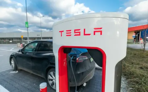 Czarna Tesla podłączona do ładowarki Supercharger.