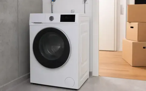 Eine weiße Waschmaschine steht neben einem Stapel Umzugskartons. Die Frage "wieviel wiegt ein trockner" ist hier nicht direkt beantwortbar, aber das Gerät ist bereit für die Wäsche.