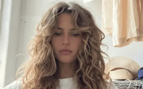 Chica con pelo rizado y flequillo desfilado, inspirador para tipos de flequillo para pelo rizado.
