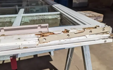 Damaged wood window frame, showing rot and peeling paint, indicating a need for wood window repair.