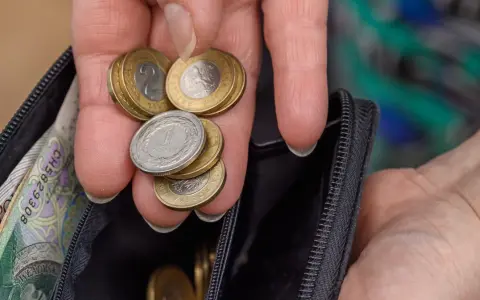 Dłoń z monetami i banknotami w portfelu. Czy to wystarczy na emeryturę po 40 latach pracy? Kalkulator emerytalny pomoże to sprawdzić.
