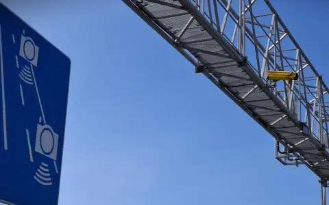 Niebieski znak informuje o odcinkowym pomiarze prędkości S7. Nad drogą widać konstrukcję z żółtą kamerą.