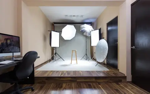 Gotowy pokój fotografa z lampami, statywami, taboretem i komputerem.