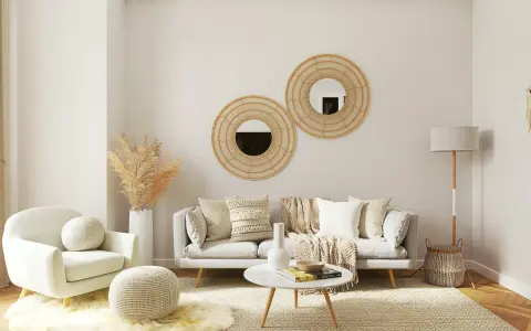 Salotto accogliente con divano grigio, poltrona bianca, tavolino rotondo e specchi decorativi in rattan. Un esempio di come arredare case moderne con stile boho-chic.