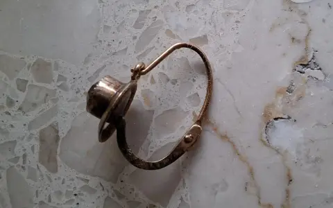 Orecchino d'oro con pietra scura, un po' consumato dal tempo, segno che l'oro si ossida.