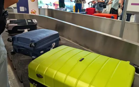 Walizki na taśmie bagażowej. Zastanawiasz się, co zabrać na wakacje all inclusive? Oto inspiracja!