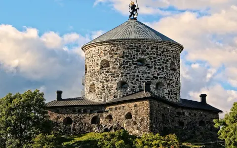 Skansen Lejonet, ett stendäckat torn med en gyllene lejonstaty på toppen, reser sig mot en molnig himmel.